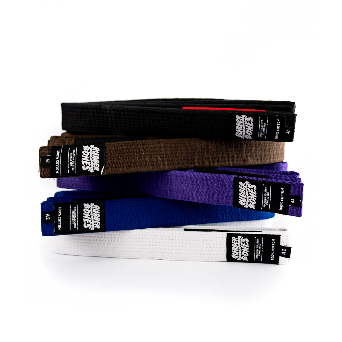 Stack of adult BJJ belts in black, brown, purple, blue, and white with Rubber Bones branding.