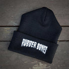 Flat lay of Rubber Bones Black Beanie featuring embroidered logo.