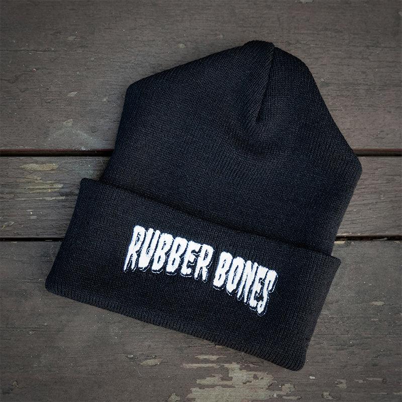Flat lay of Rubber Bones Black Beanie featuring embroidered logo.
