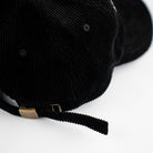 Back view of black corduroy dad hat with adjustable strap and metal clasp