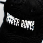 Close-up of white embroidered Rubber Bones logo on black corduroy hat