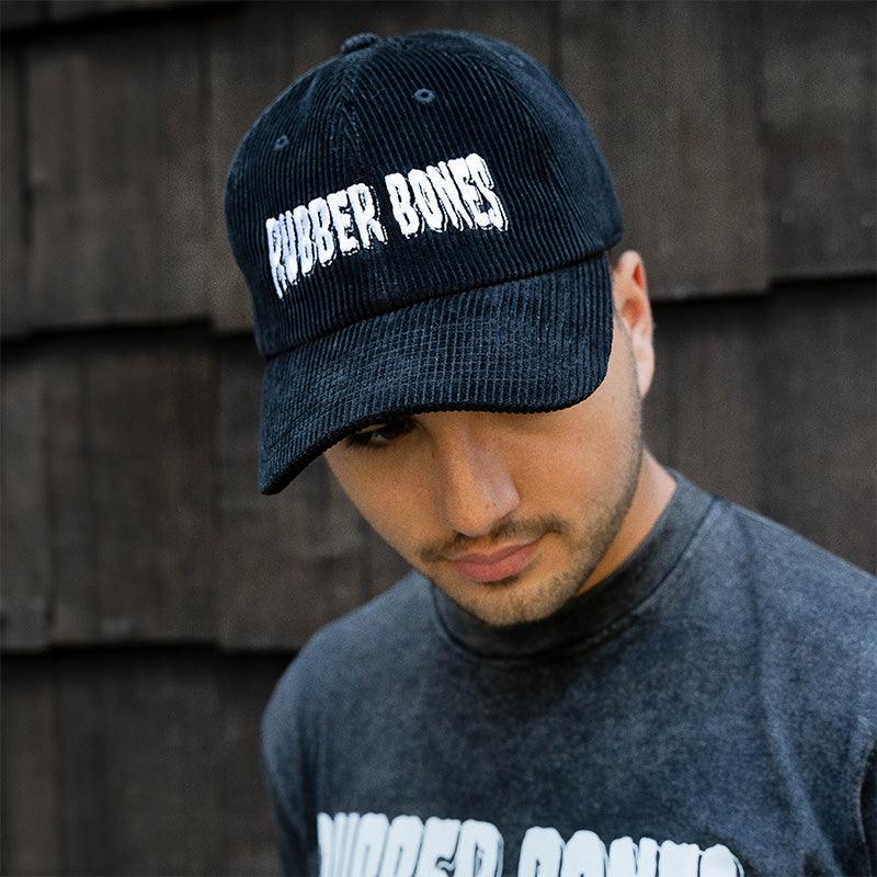 On-body 3/4 view of Rubber Bones Black Corduroy Dad Hat showing bold embroidered logo and relaxed fit.