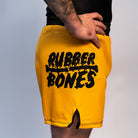 Volt Ranger BJJ Shorts (Side View on Model) – A close-up of the side of the yellow BJJ shorts, showing the Rubber Bones logo in black on the left leg and black trim on the side slit.