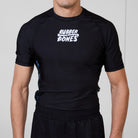 Model wearing the Men’s Ash BJJ Rash Guard featuring a black body, white Rubber Bones logo, and subtle marble side details.