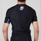 Back view of the Men’s Ash BJJ Rash Guard showing black design with white melting skull Rubber Bones logo near neckline.