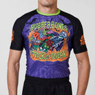 Model wearing the Trick or Treat rash guard, featuring purple, black, and neon green design with spooky graphics.