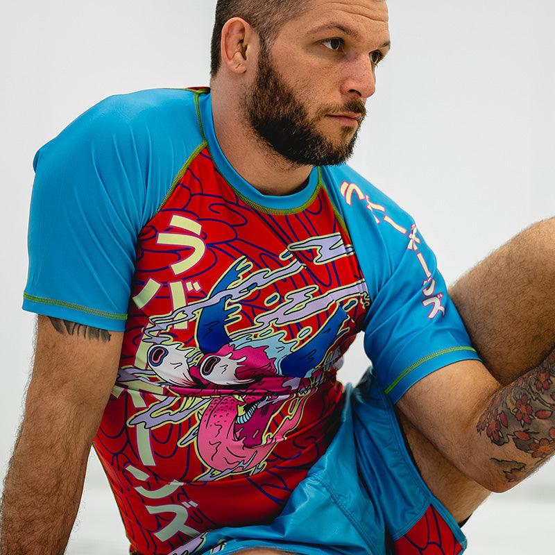 On-body shot of Hannya Drip Rash Guard in red with blue sleeves, paired with matching grappling shorts, front view.