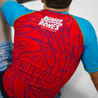 On-body shot of Hannya Drip Rash Guard in red with blue sleeves, paired with matching grappling shorts, back view.