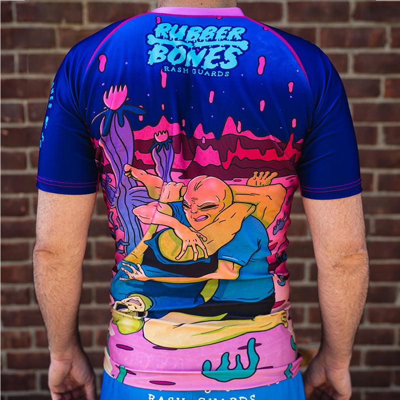 On-body back view of Invasion Short Sleeve Rash Guard highlighting alien and UFO-inspired designs.