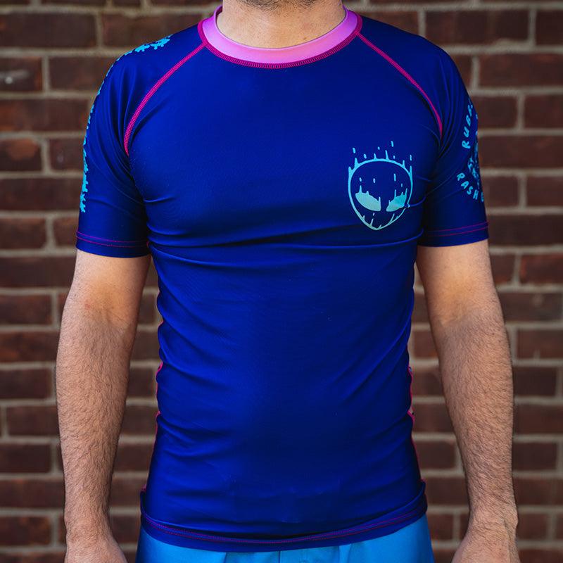 On-body front view of Invasion Short Sleeve Rash Guard with bold alien-inspired artwork.