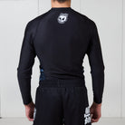 Back view of the Men’s Long Sleeve Ash BJJ Rash Guard showing black design with white melting skull Rubber Bones logo near neckline.