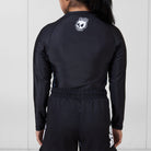 Back view of the Women’s Long Sleeve Ash BJJ Rash Guard showing black finish with melting skull Rubber Bones logo and marble side accents.