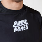 Close-up of white Rubber Bones logo printed on the chest of the Men’s Long Sleeve Ash BJJ Rash Guard.