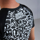 On-body close-up detail view of Ranked Rash Guard - Black highlighting Rubber Bones logo on the back.