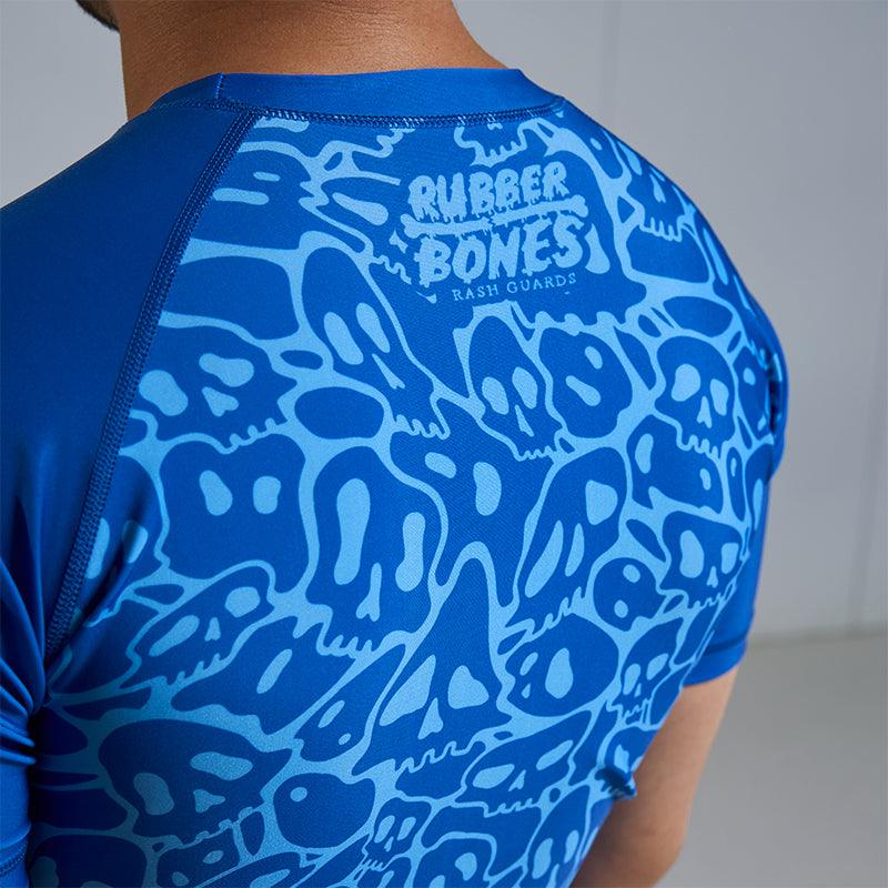 On-body back view of Ranked Rash Guard - Blue highlighting sleek monochromatic skull web design.
