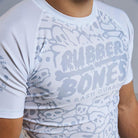 On-body 3/4 view close-up of Ranked Rash Guard - White showcasing Rubber Bones logo and skull web pattern.