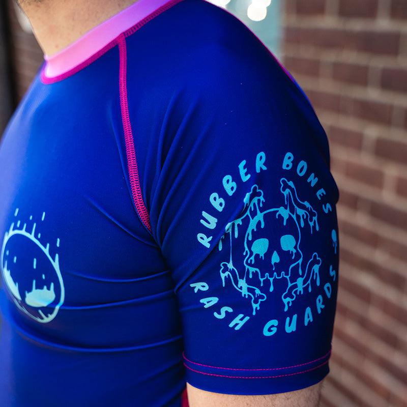 On-body 3/4 view close-up of Invasion Short Sleeve Rash Guard sleeve featuring Rubber Bones logo.