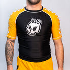 Volt Ranger Rash Guard on Model (Front) – A male model wearing the Volt Ranger BJJ rash guard, showing the fit and design with a black body, yellow sleeves, and a white skull logo on the chest.