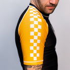 Volt Ranger Rash Guard Sleeve Detail – Close-up of the yellow sleeve on the Volt Ranger BJJ rash guard, featuring a white checkerboard pattern and visible stitching.