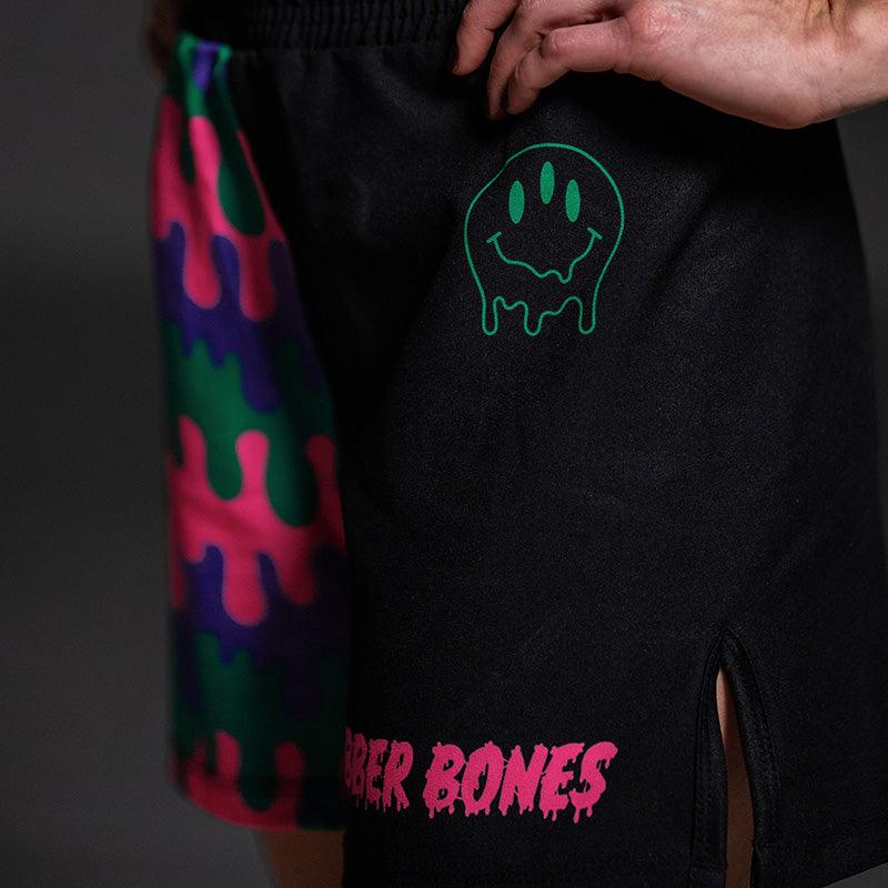Close-up of the Bubble Gum Grappling Shorts with a dripping green smiley face and pink Rubber Bones logo.
