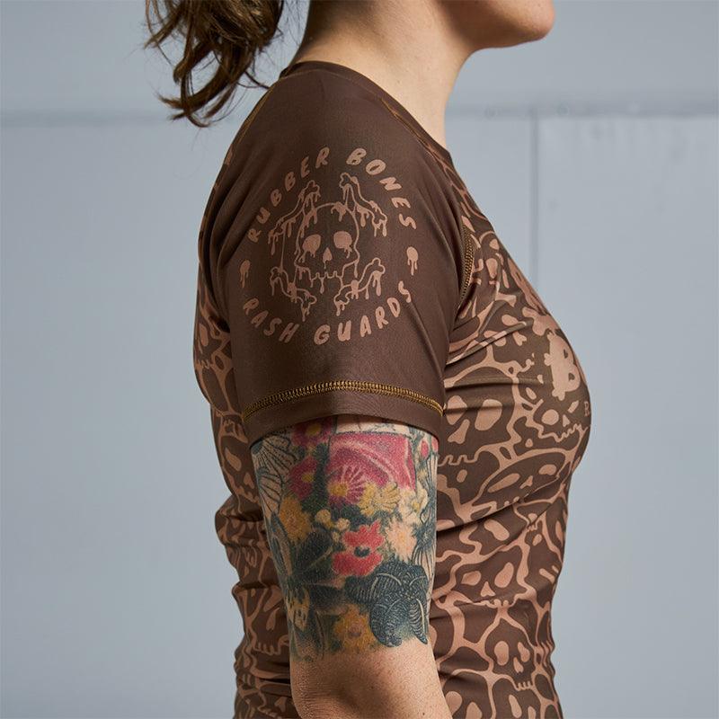 On-body side sleeve view of Women's Brown Ranked Rash Guard featuring Rubber Bones logo.
