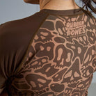 On-body 3/4 back close-up of Women's Brown Ranked Rash Guard highlighting the Rubber Bones logo.