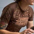On-body 3/4 front view of Women's Brown Ranked Rash Guard showcasing the fit and skull web pattern.