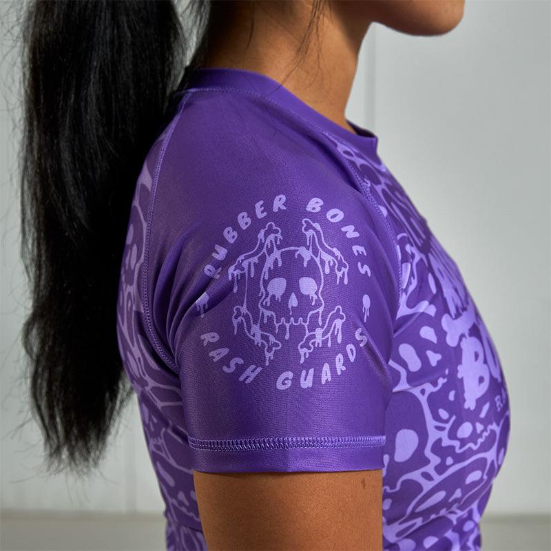 On-body side sleeve view of Women's Purple Ranked Rash Guard featuring Rubber Bones logo.