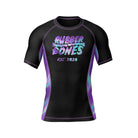 A black short-sleeve BJJ rash guard with "Rubber Bones" in a holographic-style font, blending purple, blue, and pink hues. "Est. 2020" is written below in a stylized font. The side panels feature a gradient holographic effect.