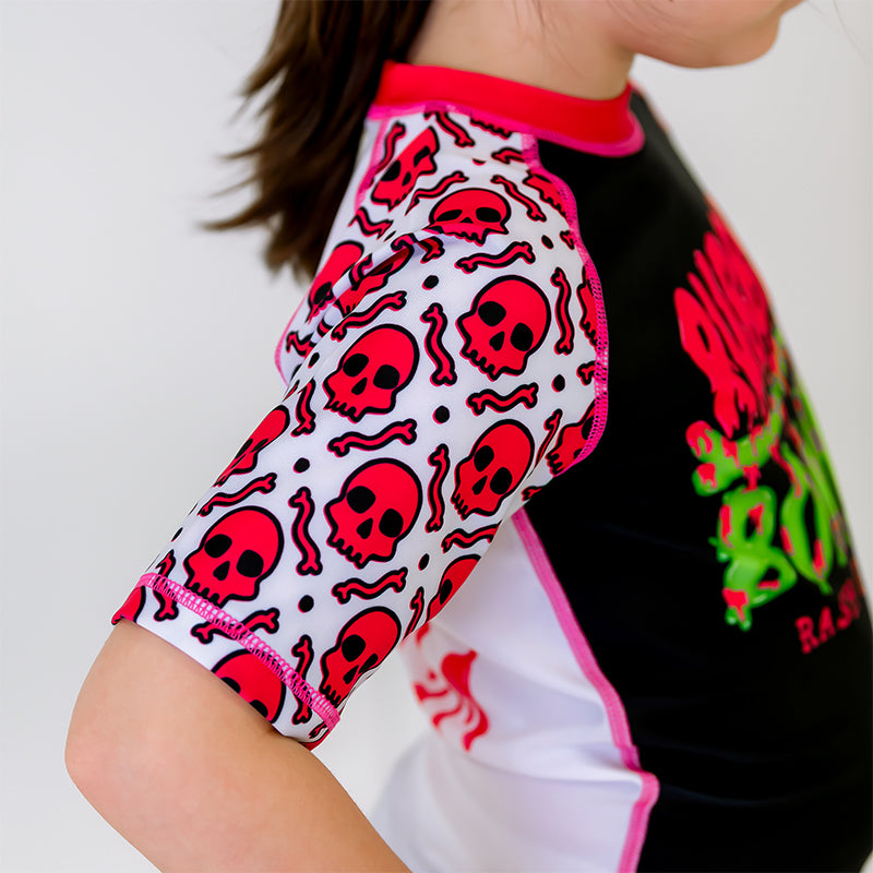  Close-up of the right sleeve of the OG Kids BJJ Rash Guard, white with a pink skull pattern.