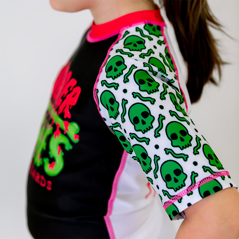 Close-up of the left sleeve of the OG Kids BJJ Rash Guard, white with a green skull pattern.