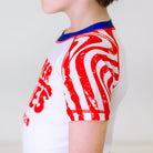 Independence Kids BJJ Rash Guard, left side view, showcasing trippy red stripes on the left sleeve with a white body.