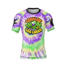 Tie-dye short-sleeve BJJ rash guard with a bold 'Legalize Leg Locks' graphic on the chest, featuring illustrated grappling-themed leaves with expressive faces. Sleeves include additional branding and graphics.