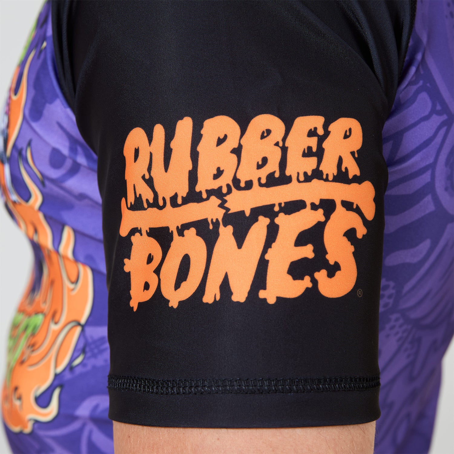 Close-up of orange Rubber Bones logo printed on black sleeve.
