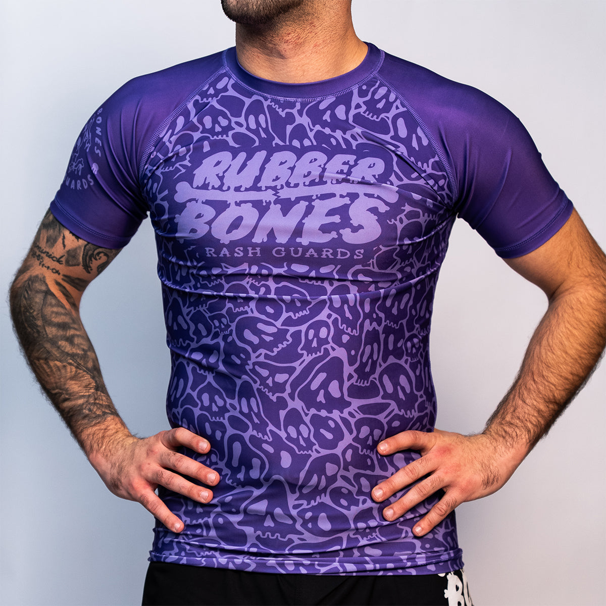 Front view of the Rubber Bones Ranked Purple BJJ rash guard – Purple compression rash guard with an all-over skull pattern and large Rubber Bones logo on the chest.