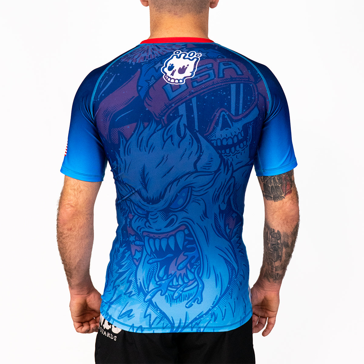 Men's Yeti Games short sleeve rash guard back view showing skeleton skier Yeti design, white Rubber Bones skull logo, red collar band, and compression fit.