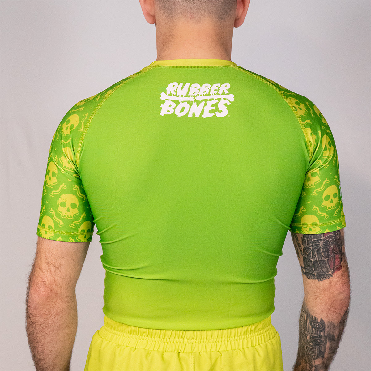 Back view of the Poison Apple men’s no gi rash guard featuring green fade body and repeating skull artwork sleeves.