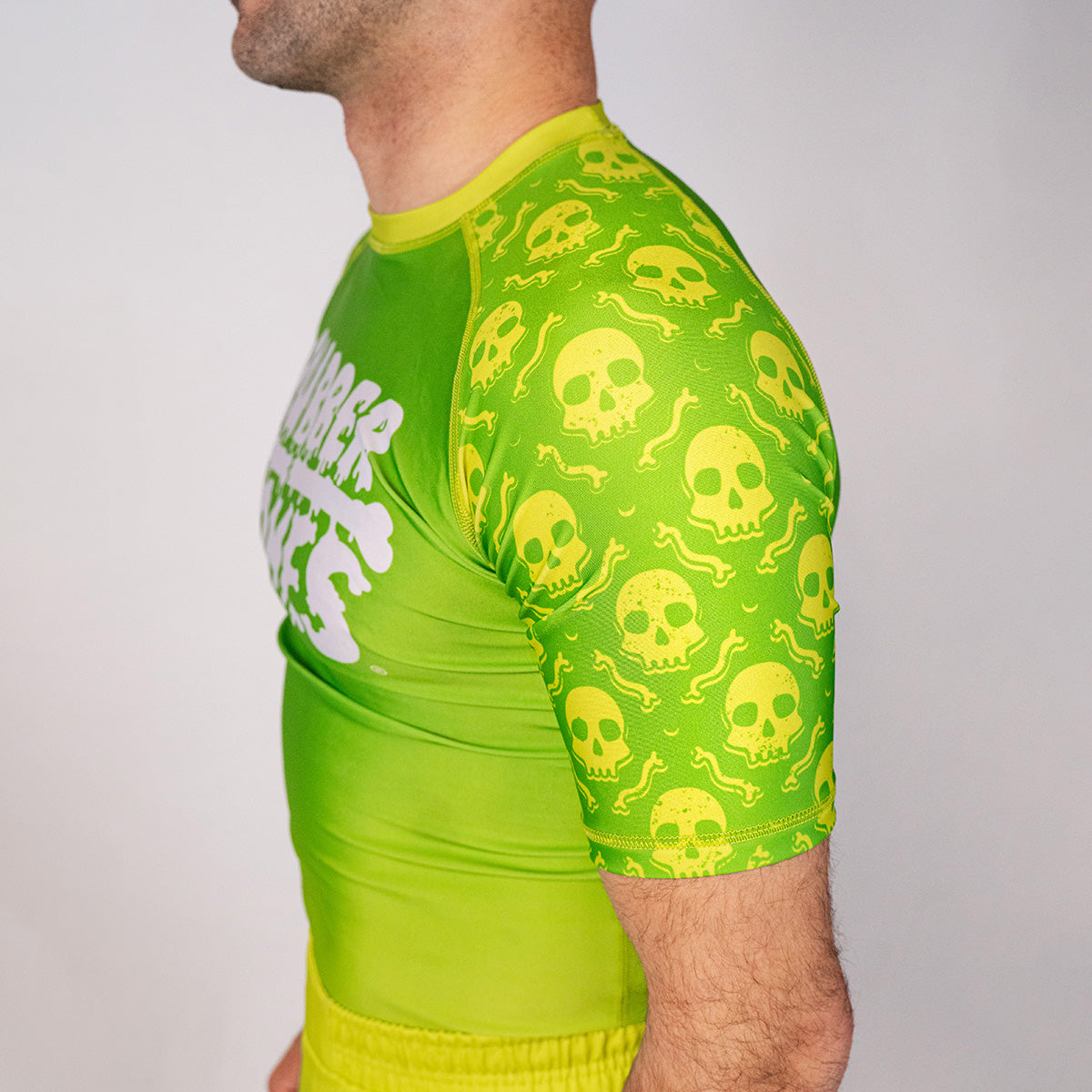 Close-up detail of the Poison Apple no gi BJJ rash guard sleeve featuring neon skull graphics and fully sublimated artwork.