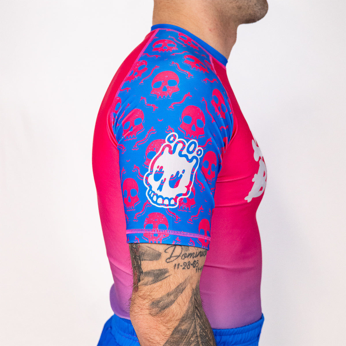 Side profile of the Toxic Berry men’s short sleeve BJJ rash guard showing blue and pink skull print sleeve artwork from the Deadly Harvest Collection.