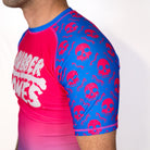 Close-up detail of the Toxic Berry no gi rash guard sleeve featuring pink skull graphics on blue fabric with fully sublimated artwork.