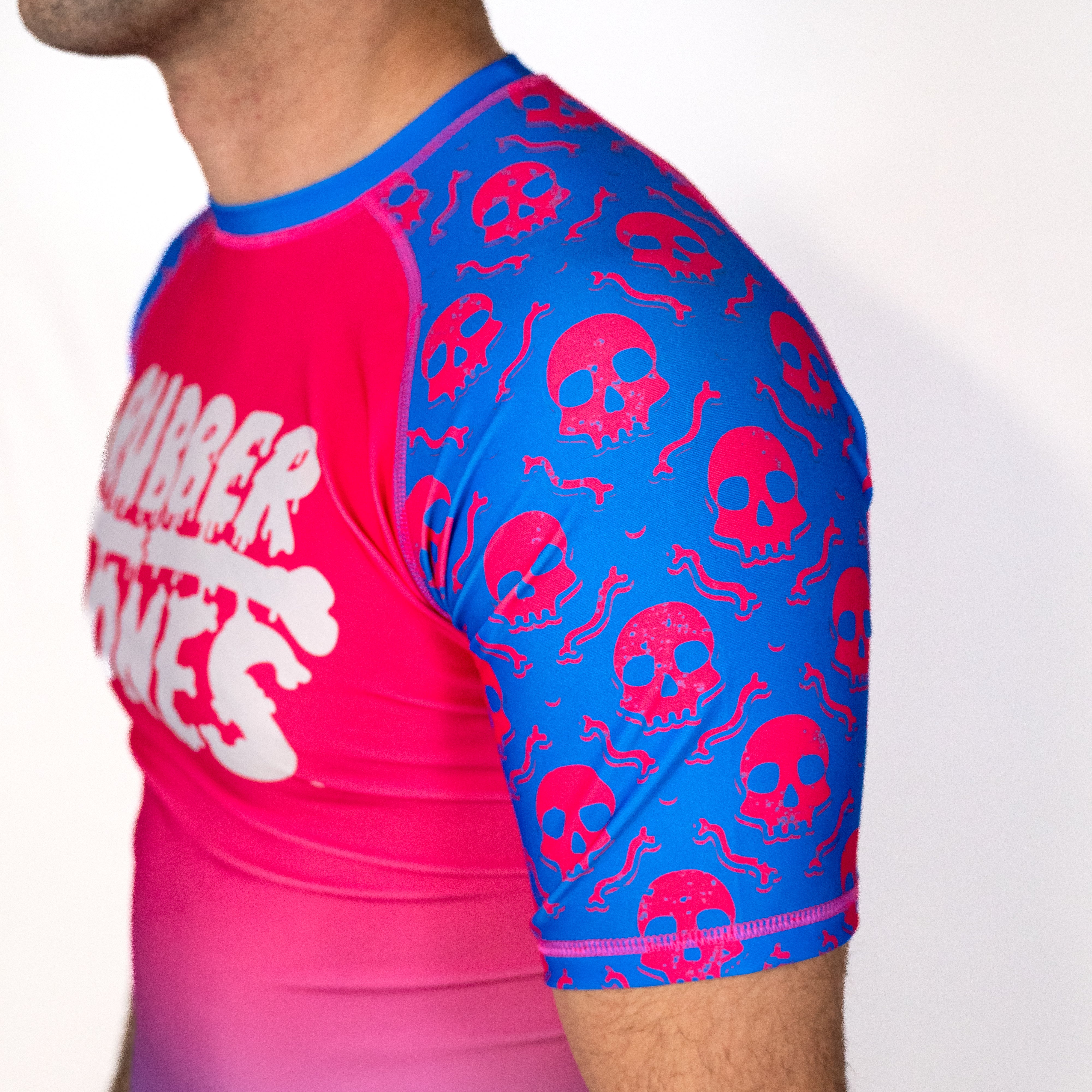 Close-up detail of the Toxic Berry no gi rash guard sleeve featuring pink skull graphics on blue fabric with fully sublimated artwork.