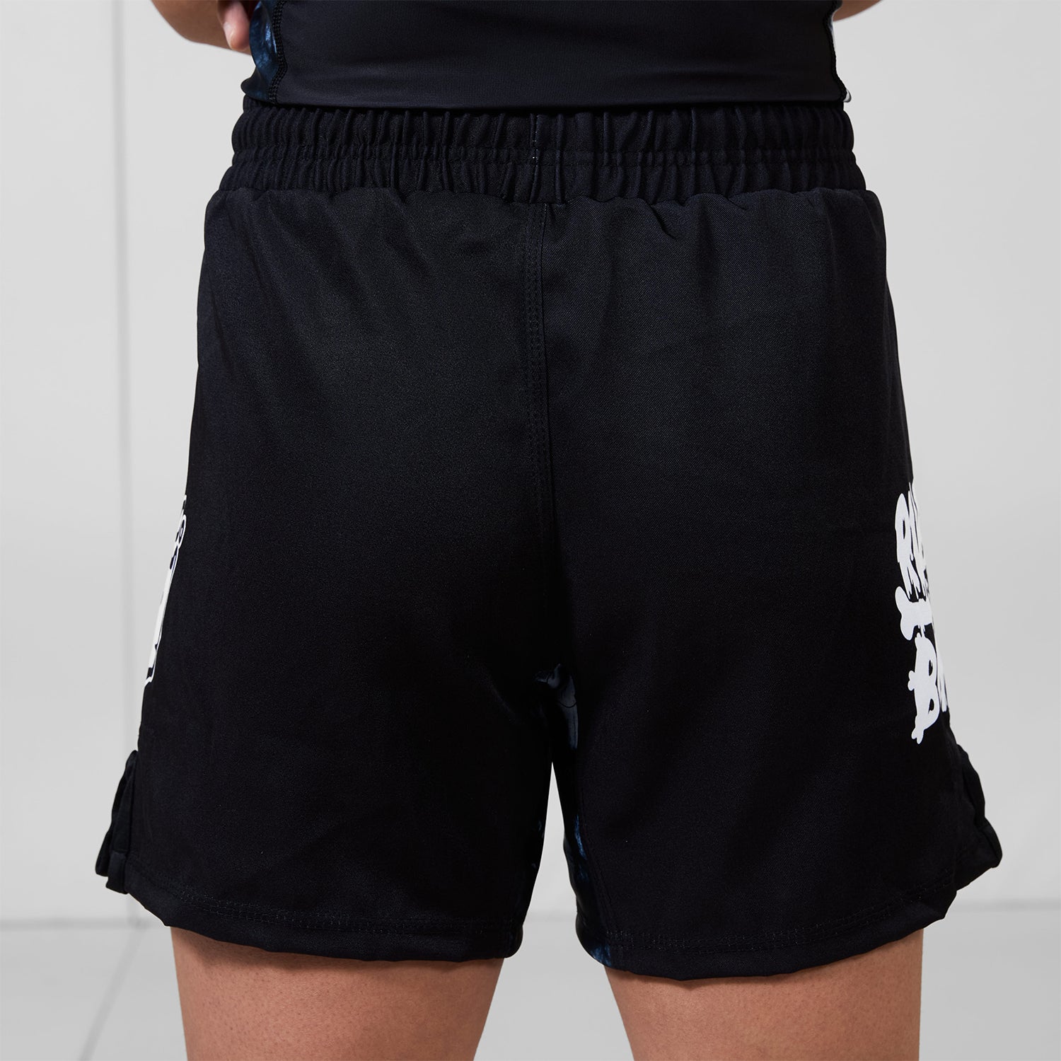 Back view of Men’s Ash BJJ Shorts showing all-black design with side logo details and elastic waistband.