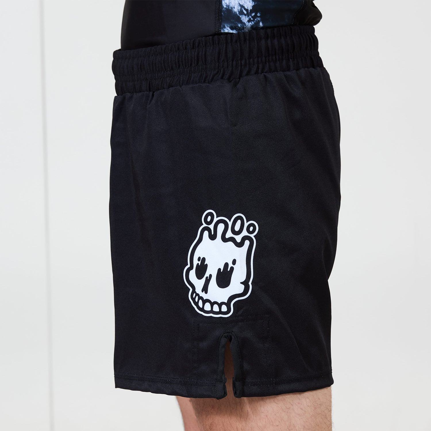 Men’s Ash BJJ Shorts side view featuring Rubber Bones skull logo and small front slit detail.