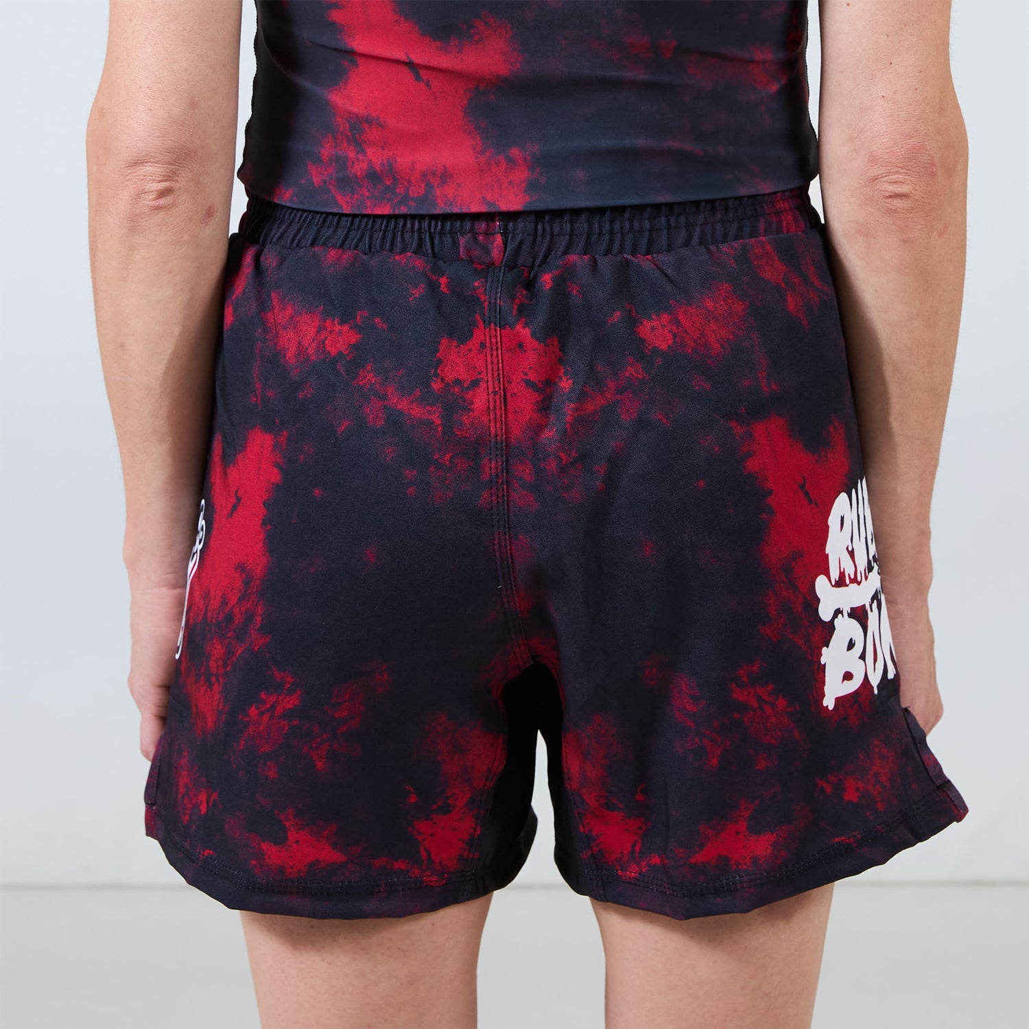 Back view of Men’s Embers BJJ Shorts showing red and black tie-dye pattern with logo details on both sides.