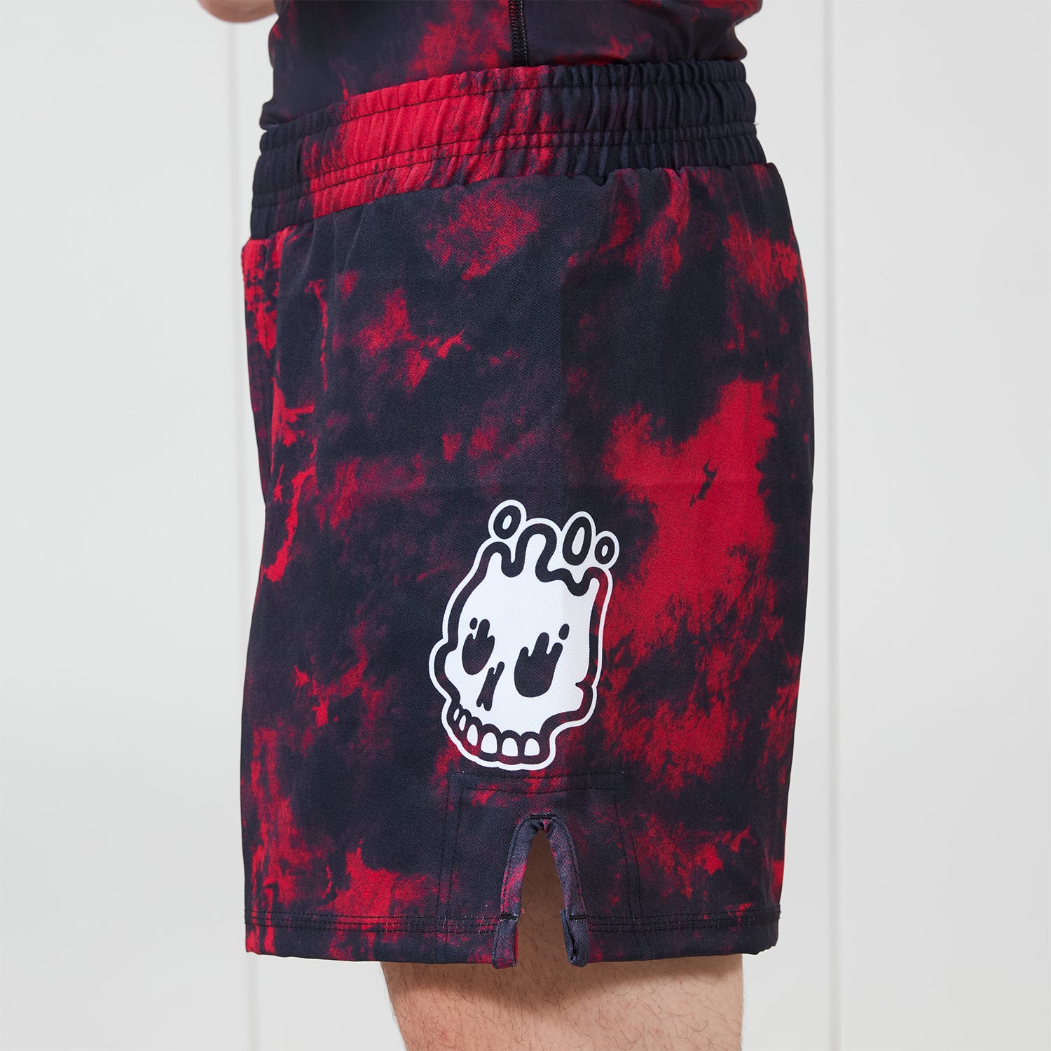 Men’s Embers BJJ Shorts side view with Rubber Bones melting skull logo on left leg, red and black marble pattern.
