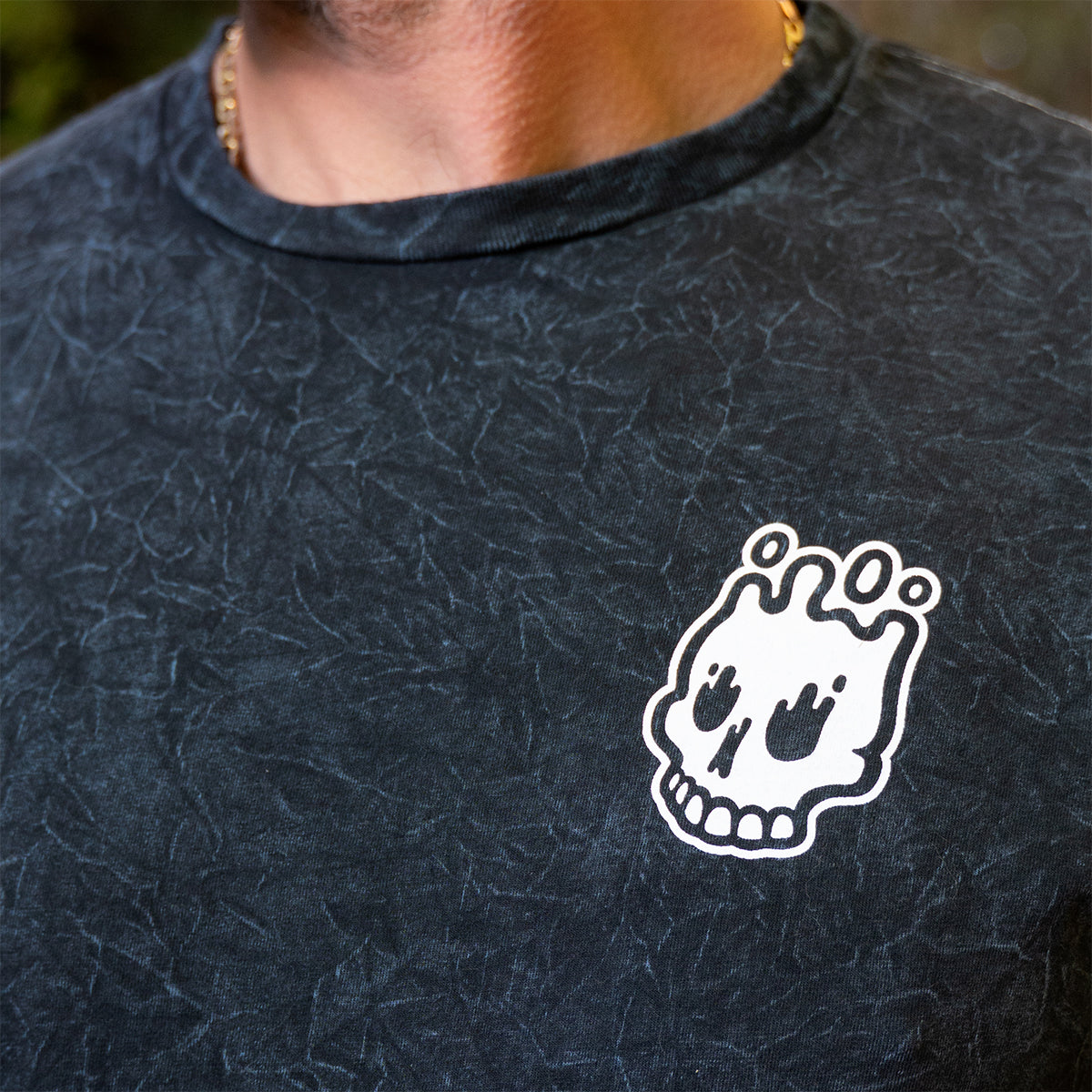 Close-up of Rubber Bones Guillotine T-shirt chest graphic showing the white melting skull logo.