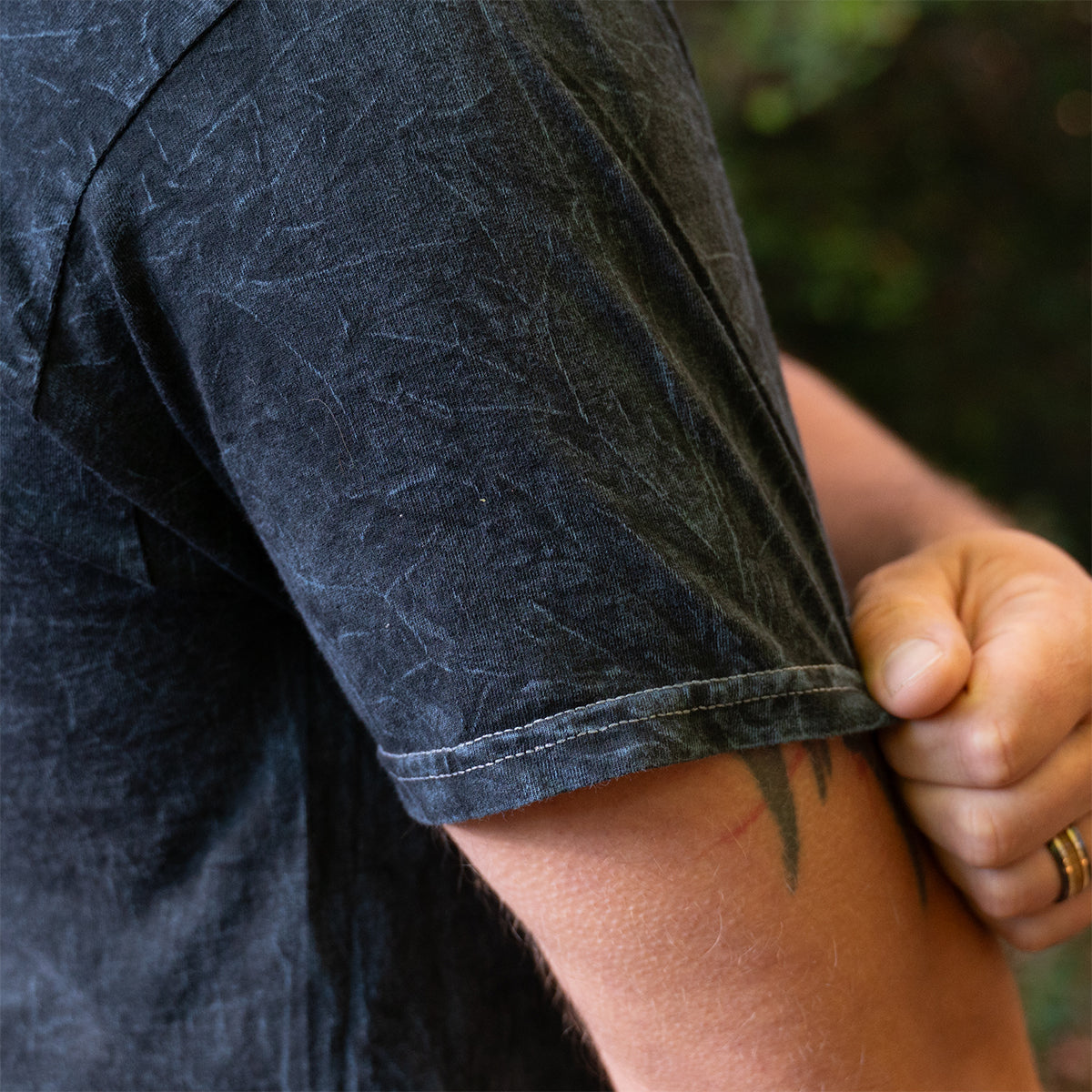 Detail of sleeve stitching and mineral wash texture on the Rubber Bones Guillotine T-shirt.