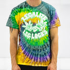 A close-up shot of a male model wearing the Rubber Bones “Legalize Leg Locks” tie-dye t-shirt. The vibrant green, yellow, and purple swirl pattern serves as the backdrop for the bold neon green graphic featuring mischievous leaf characters executing a leg lock. The design embodies the rebellious and playful spirit of Rubber Bones, perfect for grapplers who refuse to blend in.