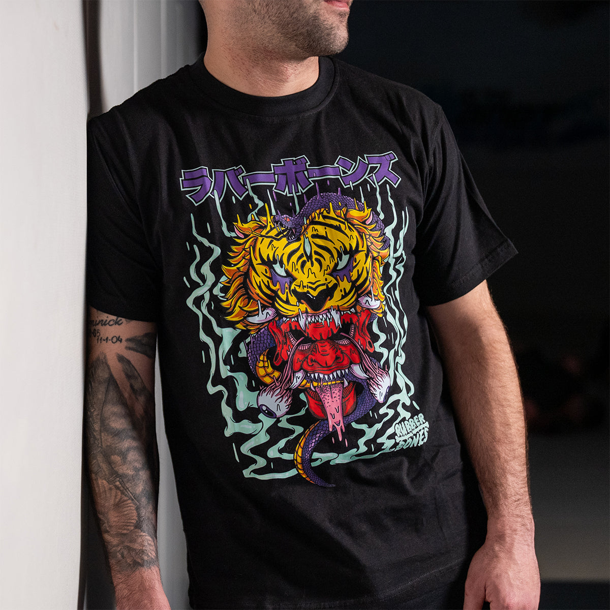 Rubber Bones Tora Oni T-Shirt – A man wearing a black BJJ streetwear tee featuring a fierce tiger-demon design with Japanese lettering. Bold, artistic apparel for grapplers and martial artists.