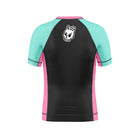 Youth-sized short-sleeve rash guard with black back panel, teal sleeves, and pink side seams. A Rubber Bones white skull logo is centered at the upper back.